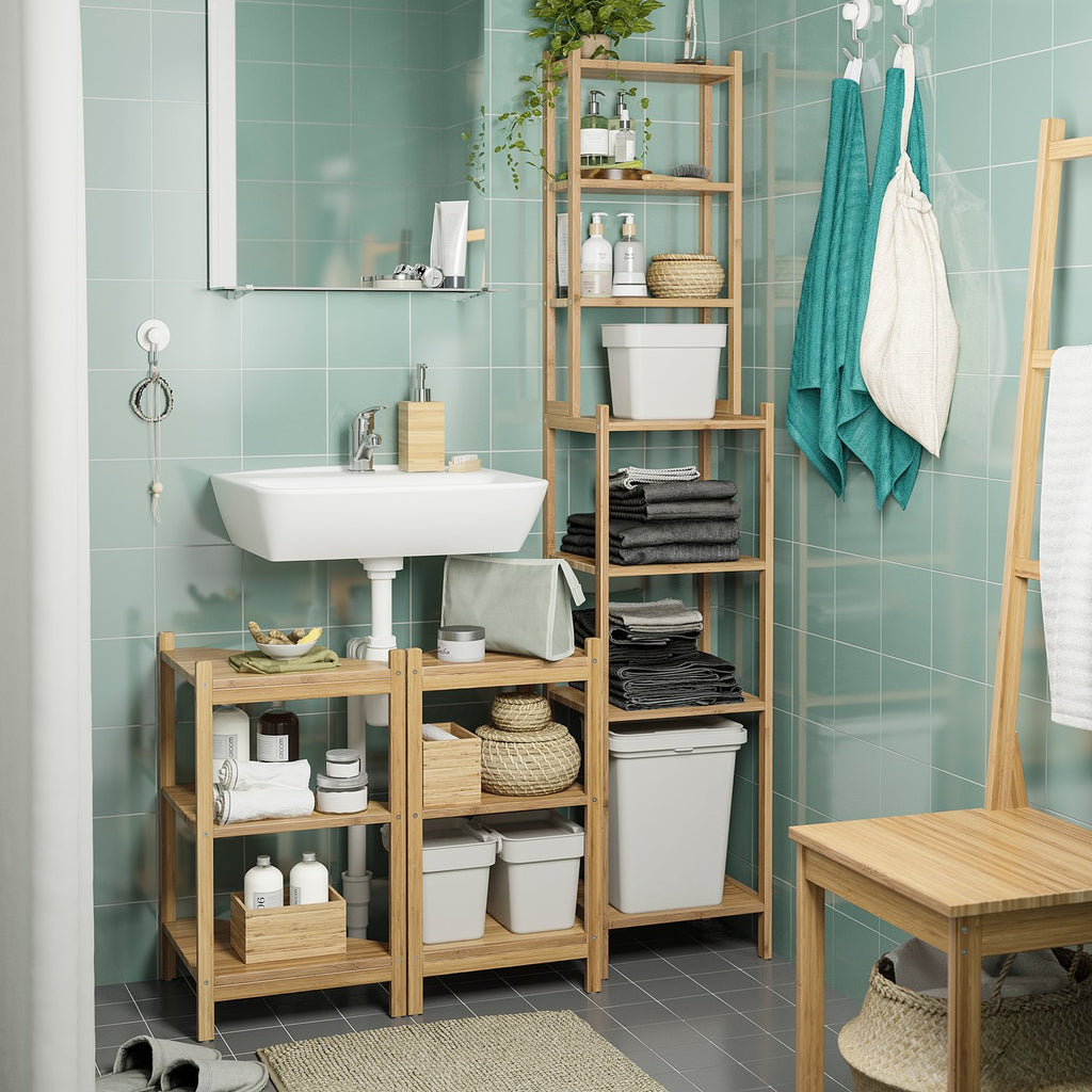 Modern bathroom with light green tiles, white sink, wooden shelves filled with white bins, towels, and plants.