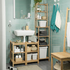 Modern bathroom with light green tiles, white sink, wooden shelves filled with white bins, towels, and plants.