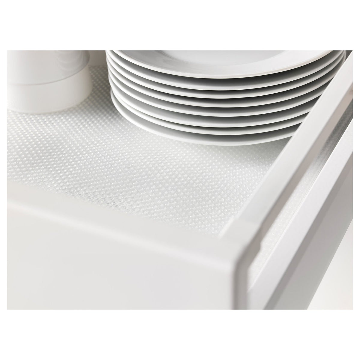 Stack of white plates on a perforated drawer mat. The mat protects shelves and dampens noise.